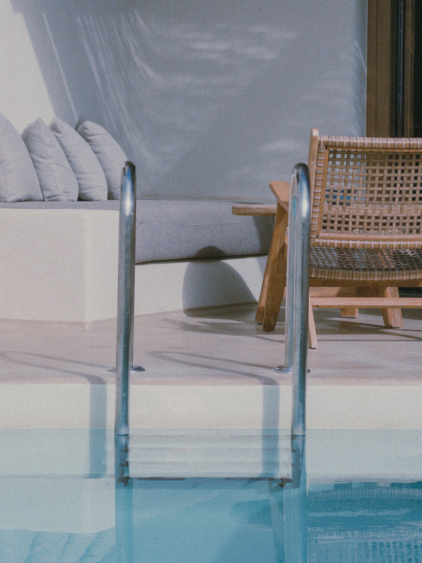 Luxury poolside terrace with sunloungers and steps to the water, Mykonos, Greece